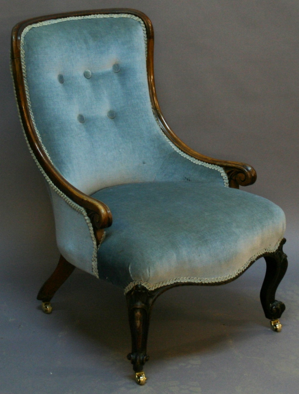 A VICTORIAN WALNUT FRAMED NURSING CHAIR having a padded buttoned back, low scrolled arms and