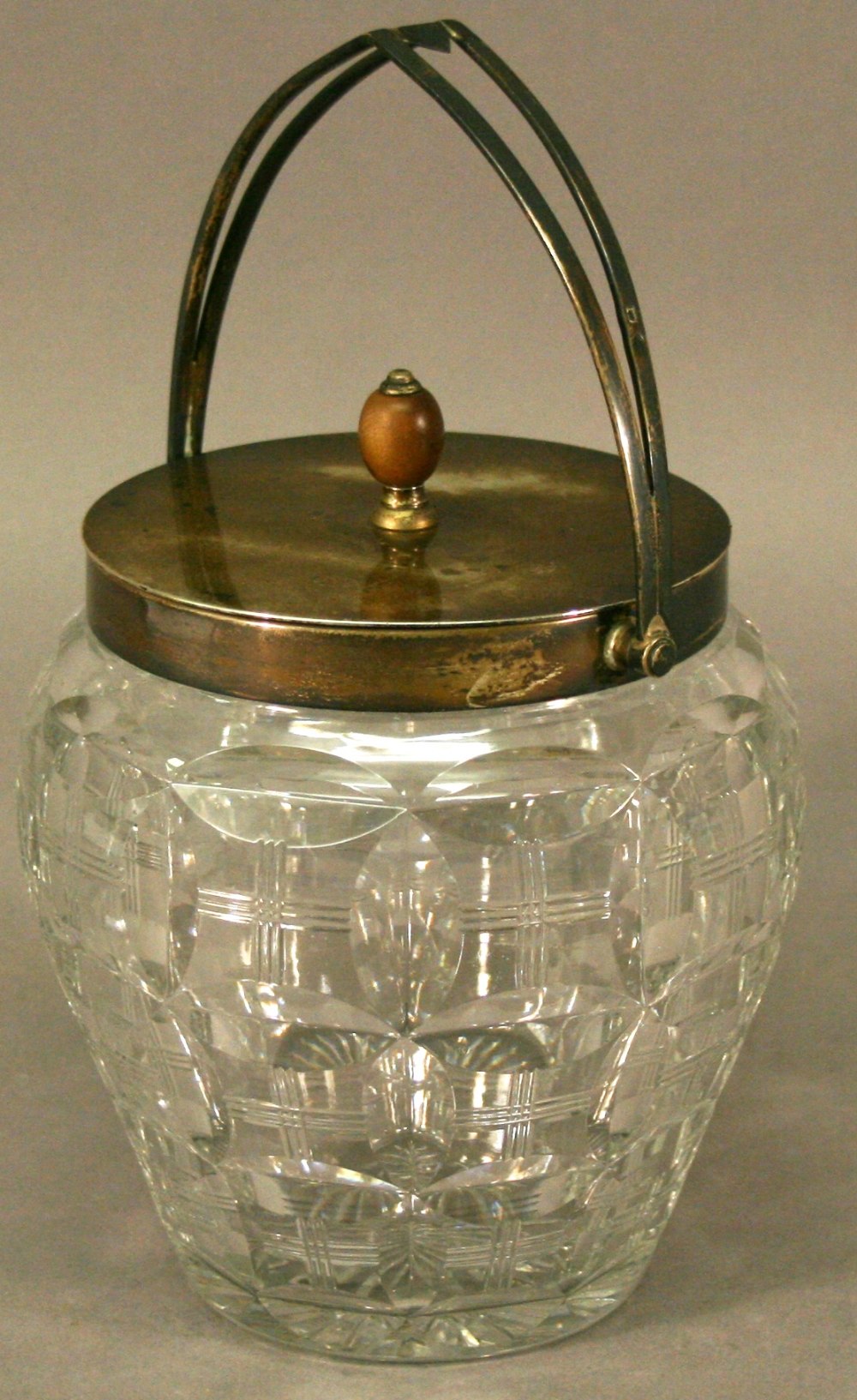 A GEORGE V SILVER-MOUNTED CUT-GLASS BISCUIT BARREL with arched swing handle and plain finial