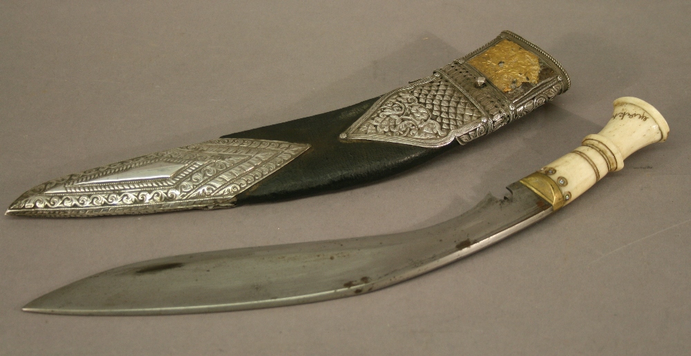 A BONE-HANDLED NEPALESE KUKRI, the bone handle signed, the leather scabbard with embossed white