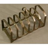 A GEORGE V SILVER TOAST RACK of oblong form with seven canted dividers and central shaped handle,