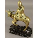 A CHINESE BRASS FIGURE of a Taoist man riding a deer, raised on a carved and pierced hardwood stand.