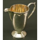 A GEORGE VI SILVER CREAM JUG of tapering cylindrical form with Celtic knot decorated rim and well