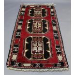 A WESTERN ANATOLIAN RUG, the vibrant red field filled with three large guls and enclosed by stylised