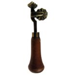 A LATE 19TH CENTURY BRASS PASTRY JIGGER with wheel and lozenge-form print and turned treen handle,