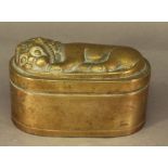 A 19TH CENTURY BRASS TOBACCO BOX of rounded oblong form, the hinged cover moulded with a recumbent