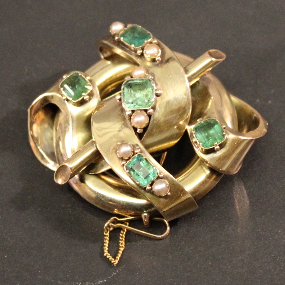 A VICTORIAN YELLOW METAL EMERALD AND PEARL BROOCH of entwined scroll, ring and rod form with inset