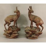 A PAIR OF BLACK FOREST CARVED WOOD MOUNTAIN GOATS modelled standing on a rocky base 45cm(h) together