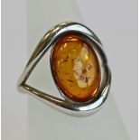 A 925 GRADE WHITE METAL AND AMBER RING, an oval amber cabochon set in a shaped open surround, marked