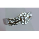 A 9CT WHITE GOLD AND DIAMOND RING the central raised flowerhead cluster between shaped shoulders