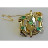 A VICTORIAN YELLOW METAL EMERALD AND PEARL BROOCH of entwined scroll ring and rod form with inset