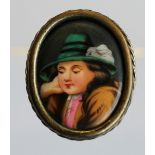 A WHITE METAL AND HAND-PAINTED PORCELAIN BROOCH of oval form, porcelain plaque painted with a