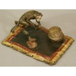 A COLD-PAINTED BRONZE INKWELL formed as a monkey, walnut and sack seated on a rug, bearing marks for