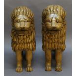 A PAIR OF LARGE CARVED PINE LIONS of stylised form with open mouths, modelled seated. 86cm(h)