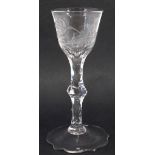 Wine glass circa 1800   the bowl engraved with exotic birds and flowers, facetted stem and shaped