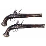 Pair of flintlock holster pistols   with flared barrels marked London, silvered mounts and carved