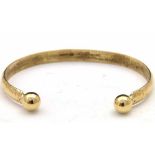 9ct gold textured slave bangle with ball ends, 15g gross.
