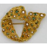 18ct gold ribbon shaped brooch set variously with small emeralds and diamonds on a textured