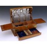 Oak tantalus and games box applied with cut brass mounts, enclosing three square decanters, two