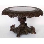 Burmese carved hardwood circular centre table, the tip top with a border of scrolling foliage,