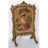 Victorian gilt wood cheval firescreen, circa 1870, the stump-work panel of a peacock in an ornate