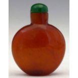 Amber effect glass snuff bottle of flattened ovoid form, domed green cap, overall height 6.3cm.