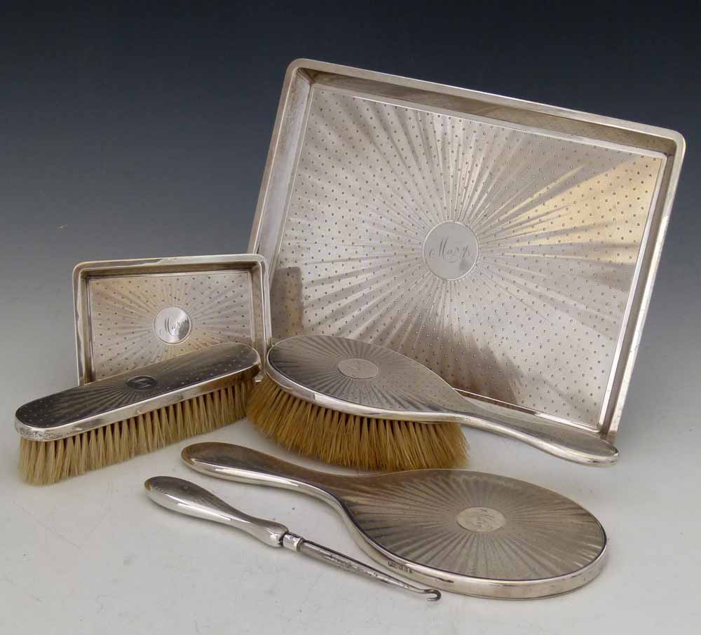 Silver dressing table set, Finnigans, London 1916 - 1924, of a hand mirror, two brushes, button hook