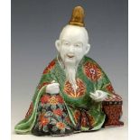 Kutani porcelain figure of a scribe, 19th century, painted in enamels, length 19cm.