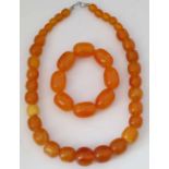 Amber-coloured graduated necklace, 50cm; and an amber-coloured bracelet. (2)