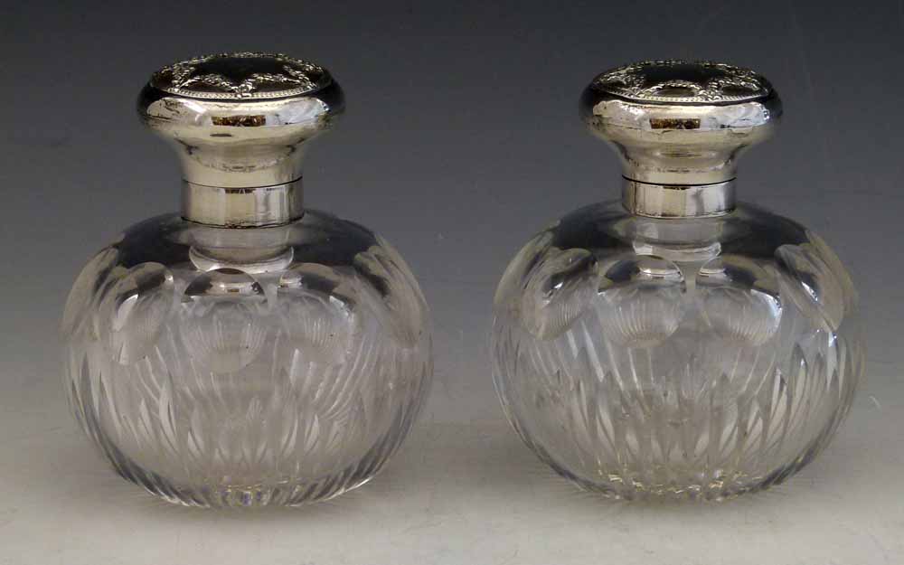 Two cut glass globular scent bottles with silver tops, London 1912,  height 11cm.