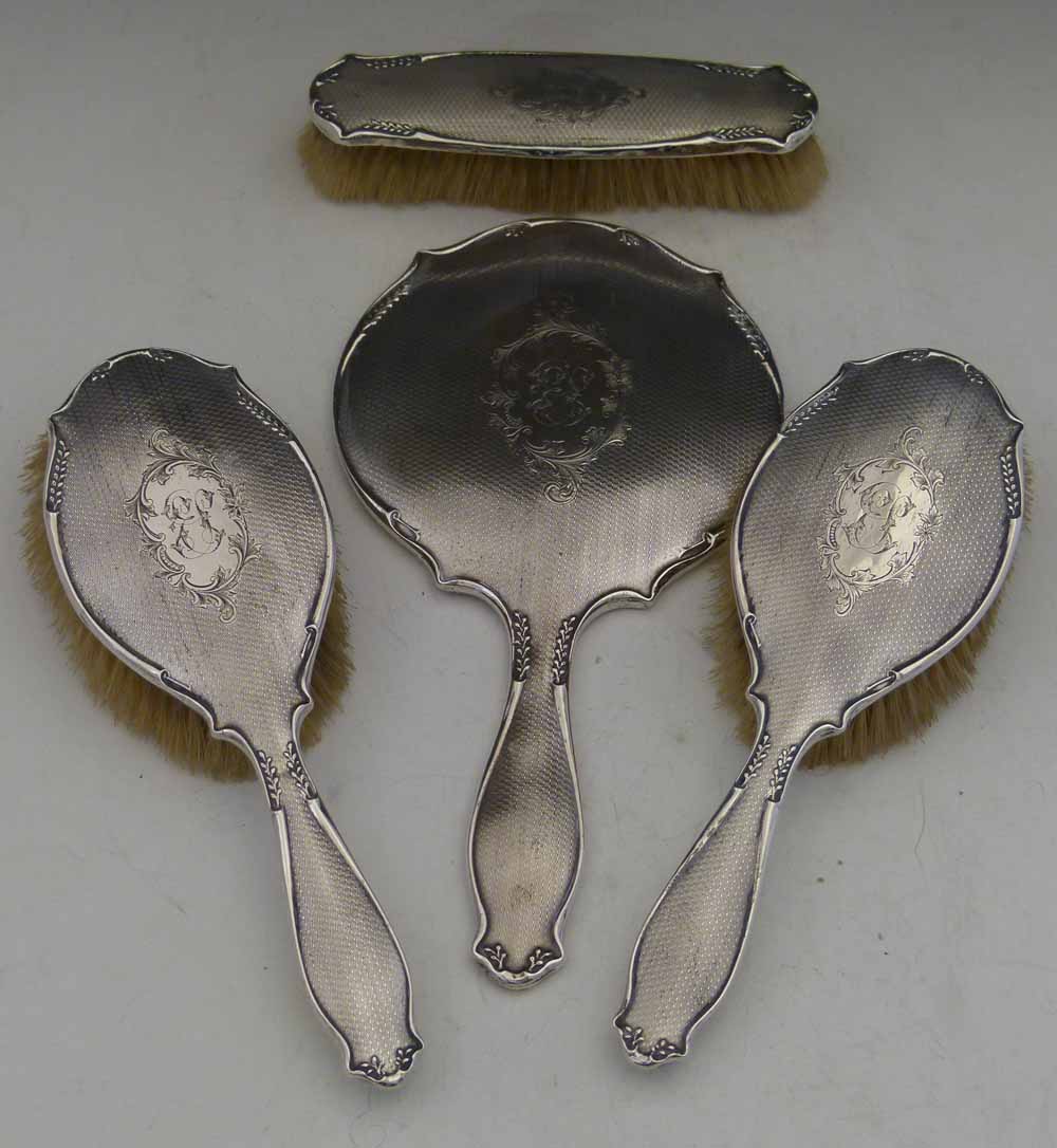 Four-piece silver backed dressing table set of three brushes and a mirror, Birmingham 1945/6.