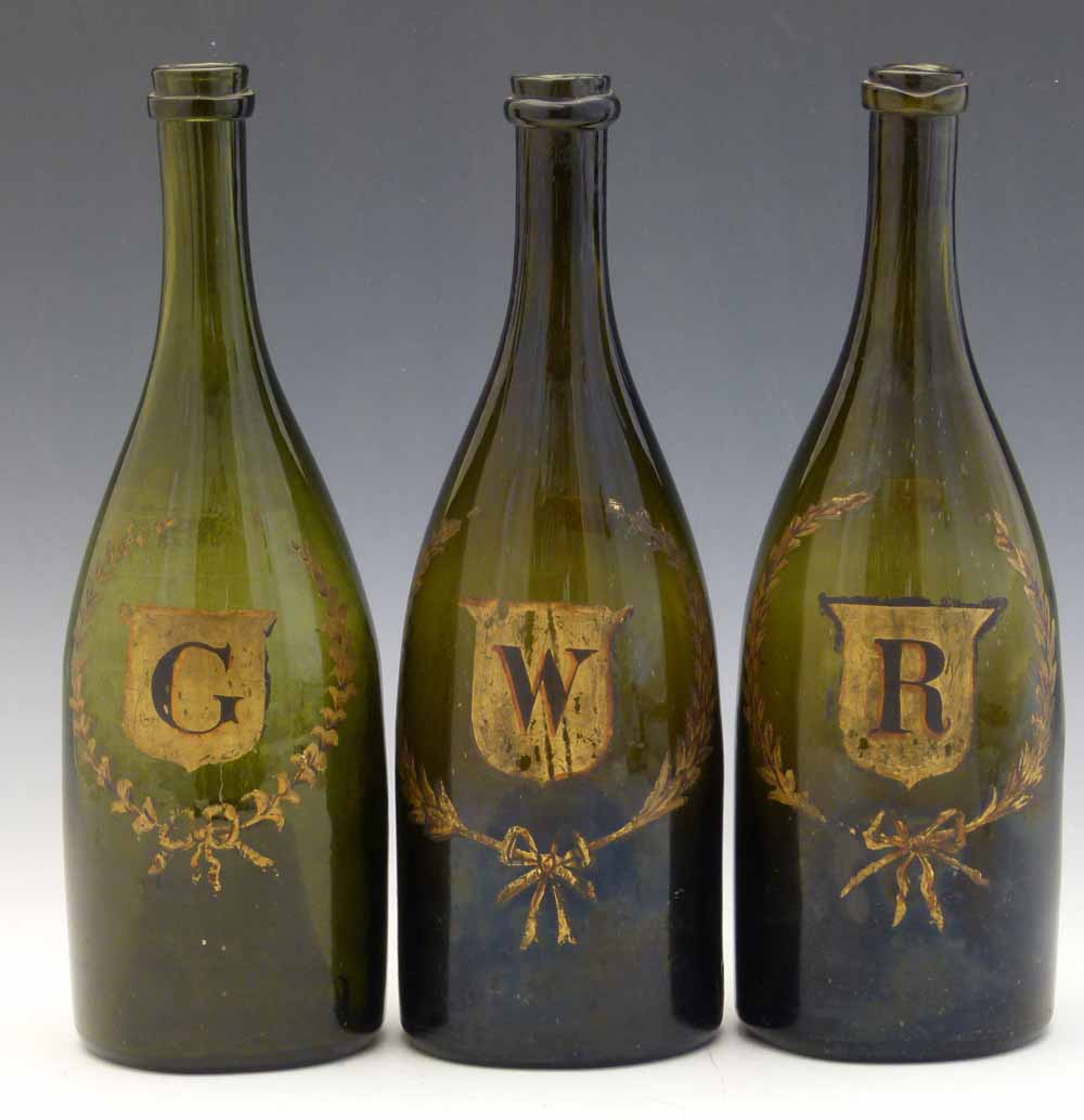 Three green glass bottles, 19th century, gilded with G, W and R each in a wreathed shield, height