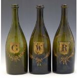 Three green glass bottles, 19th century, gilded with G, W and R each in a wreathed shield, height