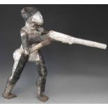 African figure holding a gun, cover with hammered tin plate, 58cm high     All lots in this Tribal