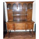 Arts & Crafts oak dresser on turned front legs with plate rack enclosing cupboards. Condition