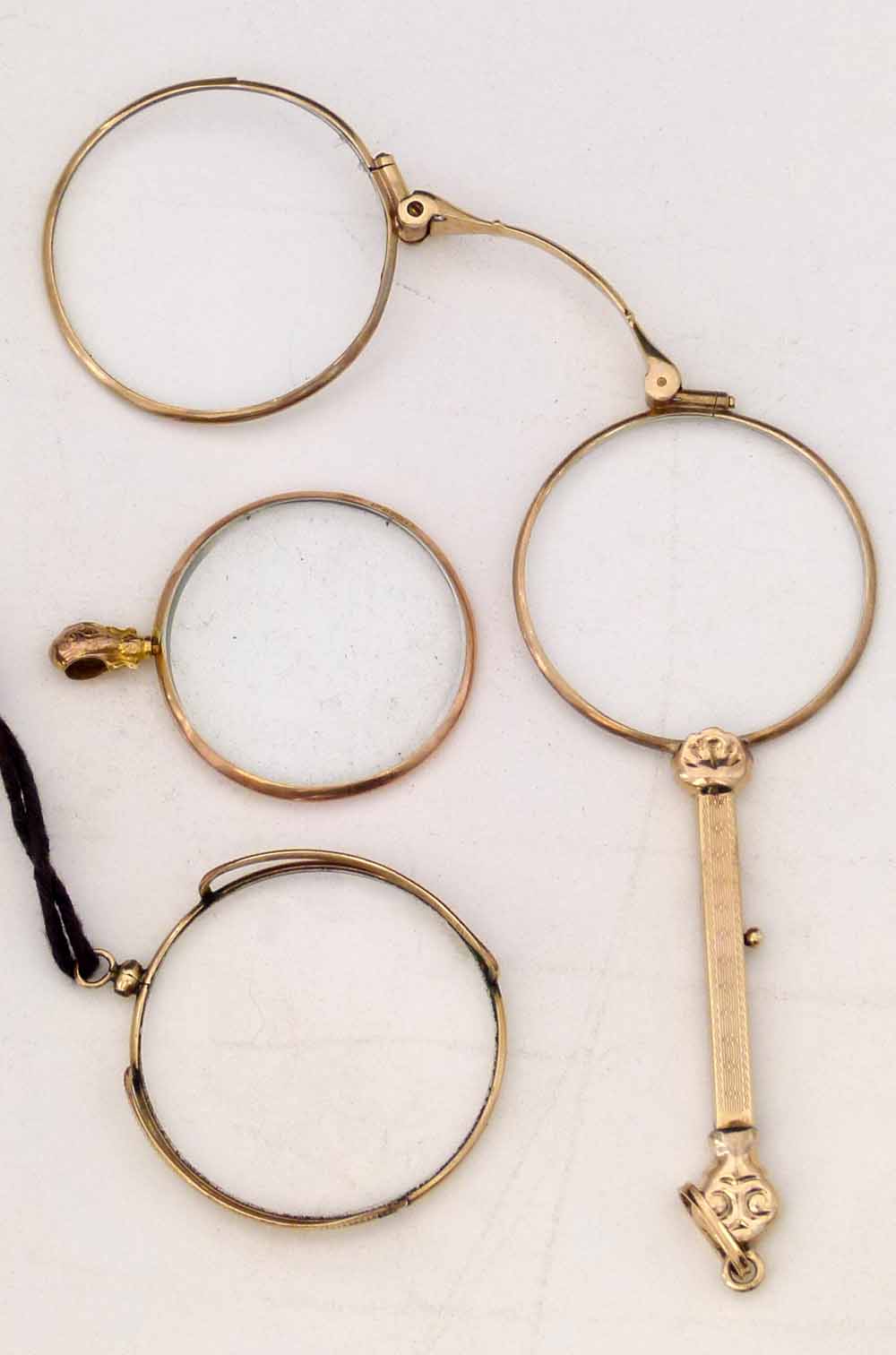 Unmarked yellow metal lorgnette with engraved decoration and a release button on the shaft, length