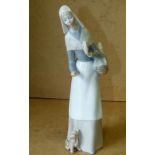 A Lladro Figure of a standing lady holdi