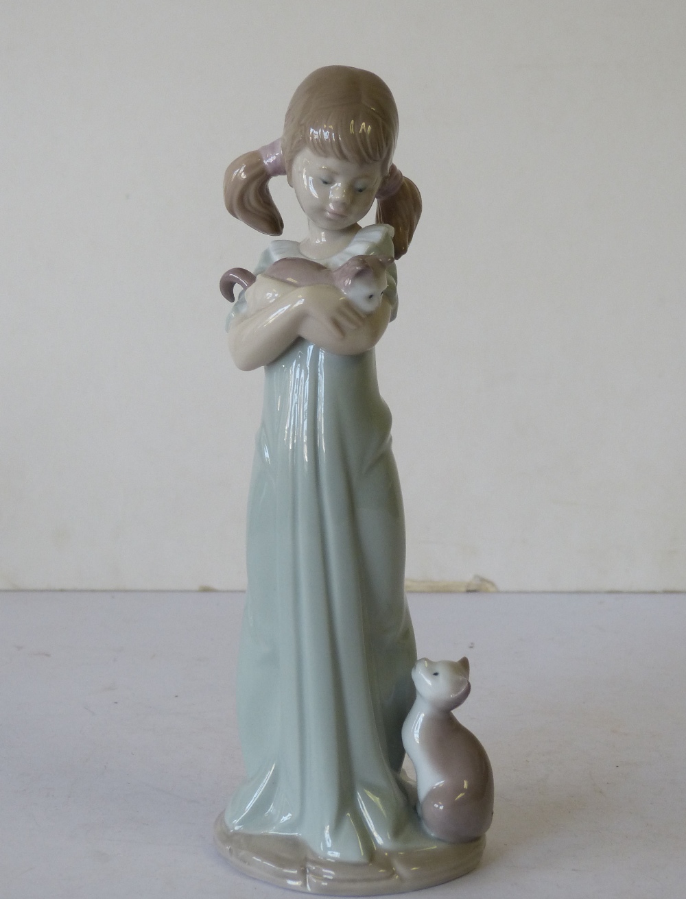 A Lladro Figure of a young girl holding a kitten with a cat at her feet, 21cm high