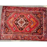 An Iranian Rug on red, brown and blue ground having centre medallions,