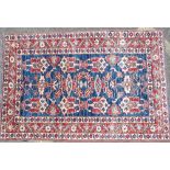 A Persian Rug on white, red and blue ground having various centre medallions,