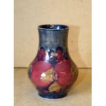 A Moorcroft Small Bulbous Thin Neck Vase on blue ground with multicoloured pomegranate decoration,