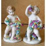 A Pair of Continental China Figures of seated children holding crusted flowers with bird motif,