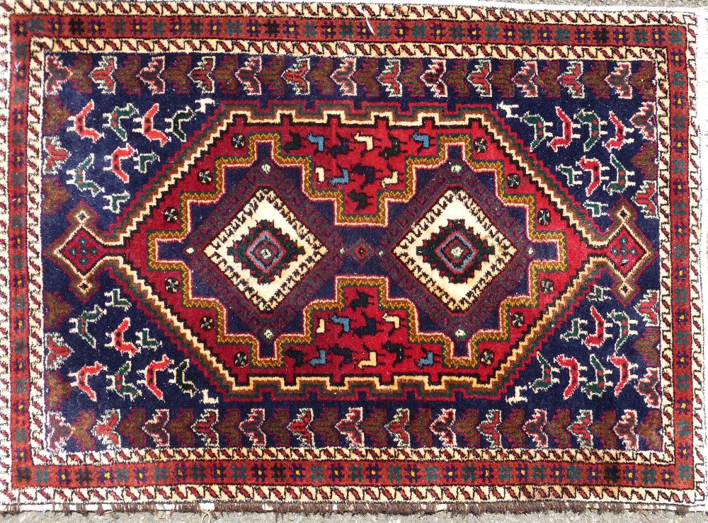 A Persian Rug on white, red and blue ground having 2 centre medallions with animal and bird motifs,