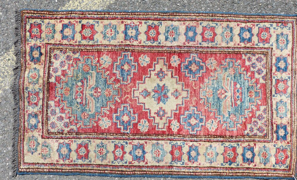 A Small Persian Rug on white, red and blue ground having 3 centre medallions,