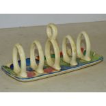 A Clarice Cliff Bizarre Fantasque 5-Bar Toast Rack having centre carrying handle with multicoloured