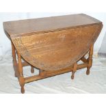 A 1920's Oak Oval Gate Leg Table having carved scroll rim on round turned legs,