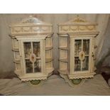 A Pair of Painted Hanging Wall Cabinets with swag, vase, floral, leaf and scroll decoration,
