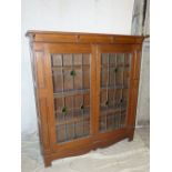 A 1920's Oak Low Display Cabinet having 2 x leaded glass panel doors enclosing shelves,