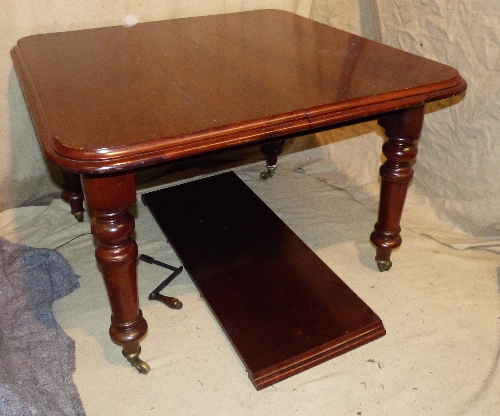 A Victorian Mahogany Key Wind Dining Table having 1 extra leaf on round turned legs with brass