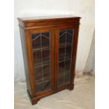 A 1920's Oak Low Bookcase having 2 leaded glass panel doors enclosing shelves on bracket feet,