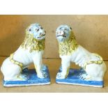 A Pair of Glazed Majolica Figures of seated lions on white, yellow and blue ground,